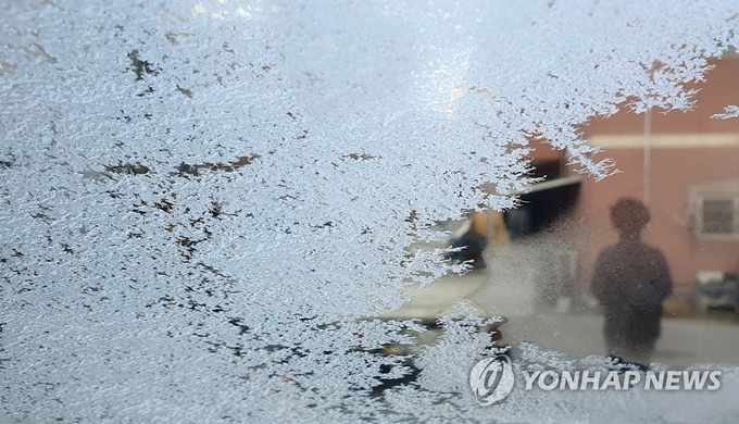 겨울이 시작되는 입동(立冬)인 8일 오전 강원 춘천시 석사동의 서리 내린 차창 너머로 한 시민이 발걸음을 재촉하고 있다