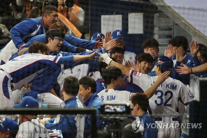 8일 오후 서울 구로구 고척스카이돔에서 열린 2019 WBSC 프리미어12 예선라운드 C조 한국과 쿠바의 경기.5회 말 2사 2루에서 한국 김재환이 김현수의 1타점 적시타 때 홈인한 뒤 더그아웃으로 들어와 동료들과 하이파이브하고 있다