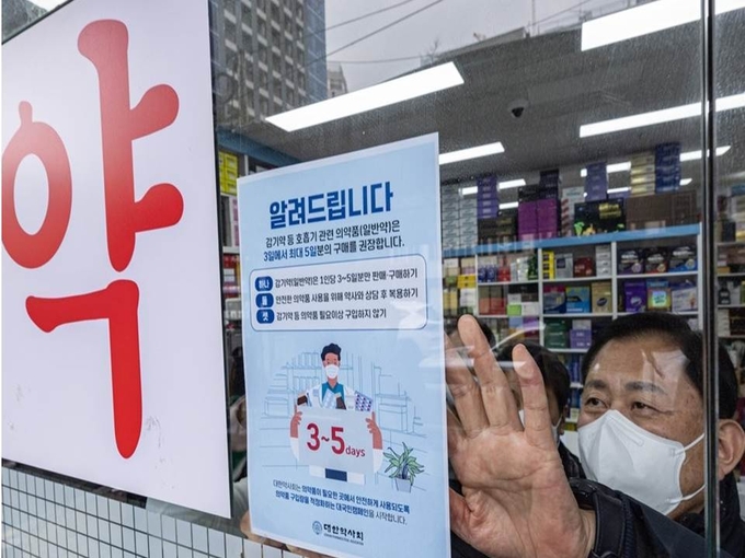 최광훈 대한약사회 회장이 31일 오전 서울 중구 남대문로의 한 약국에 감기약 수급 안정을 위해 판매를 제한한다는 내용의 안내문을 붙이고 있다.