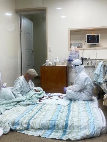 방호복을 입은 채 할머니와 화투 놀이를 하던 모습으로 온라인에서 화제가 된 사진 속 의료진은 삼육서울병원 간호사 이수련(29)씨로 밝혀졌다